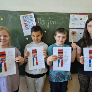 Prezentacja efektów pracy – uczniowie z plakatami powitań w pięciu językach.