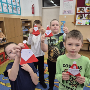 Uczniowie prezentują własnoręcznie wykonane papierowe figurki Mikołaja – efekt zajęć plastycznych inspirowanych świąteczną opowieścią o dobrych słowach.